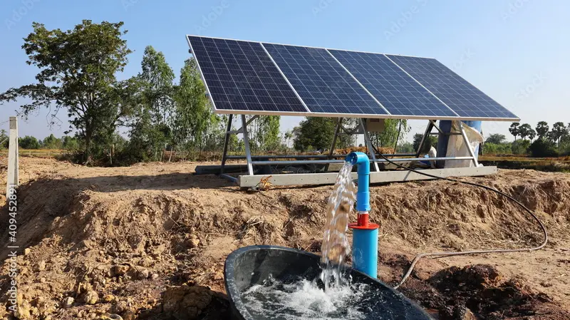 Panel solar junto a un pozo con agua saliendo de la bomba