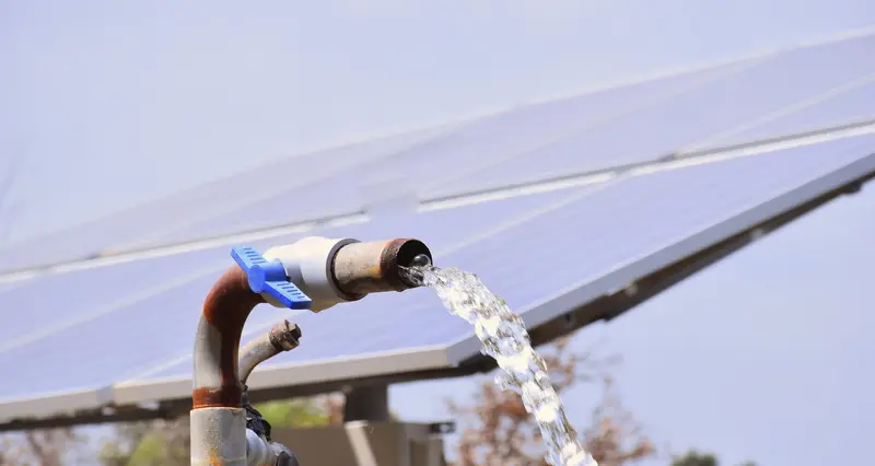 Agua saliendo de una tubería bajo un panel solar